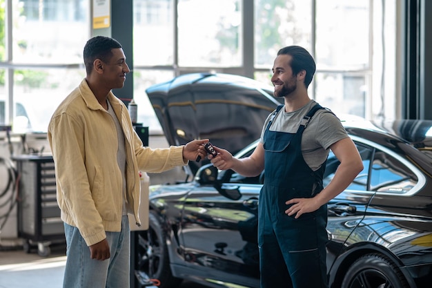 Man die autosleutel geeft aan autoreparateur