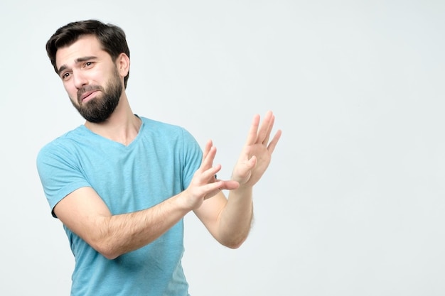 Man die bang gebaar maakt met zijn handpalmen alsof hij zichzelf probeert te verdedigen