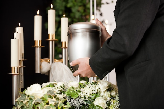 man die begrafenis urn met kaarsen en bloemen