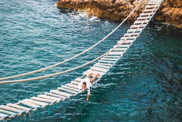 Man die bij de hangbrug ligt en geniet van uitzicht op zee en de rust van de natuur