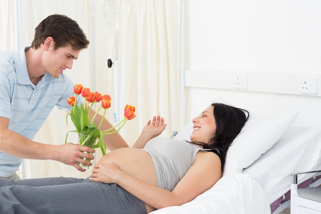 Man die bloemen aanbieden aan zwangere vrouw in het ziekenhuis