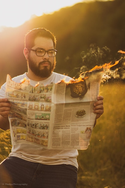 Foto man die buiten een brandende krant leest