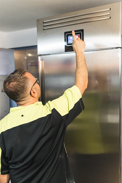 Foto man die de koelkastinstelling in de keuken aanpast en producten in de restaurantkeuken bespaart