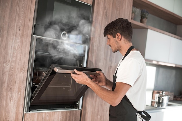 Man die de oven in de thuiskeuken opent