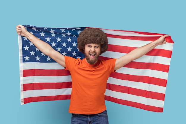 Man die de vlag van de V.S. vasthoudt en naar de camera kijkt met een vreugdevolle blik die vakantie viert