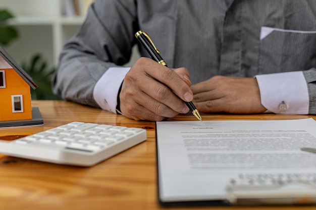 Man die documenten op tafel controleert, huisverkoper controleert op juistheid van contractdocumenten voordat klanten de deal ondertekenen. Vastgoed handelsconcept.