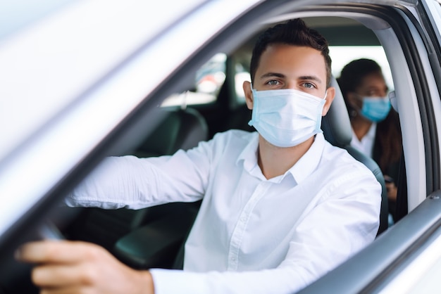 Man die een auto bestuurt met een beschermend masker tijdens in quarantainestad. Covid 19.