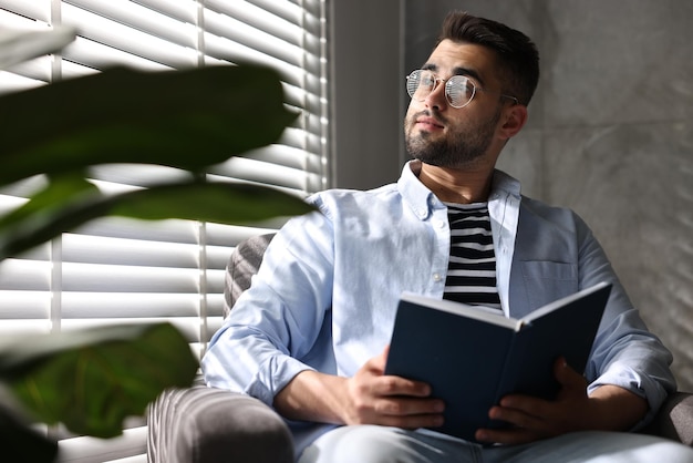 Man die een boek leest bij vensterroosters binnen
