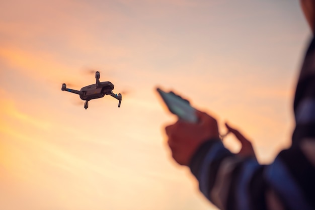 Man die een drone met afstandsbediening bestuurt in zonsondergang.