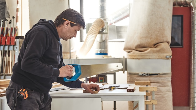 Man die een handzaag gebruikt om hout te zagen