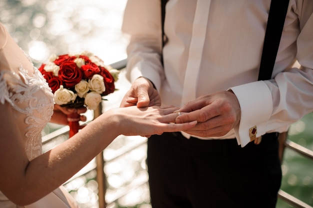 Foto man die een ring op de vinger van zijn verloofde plaatst die op de pier aan het meer staat. conceptie van de bruiloft