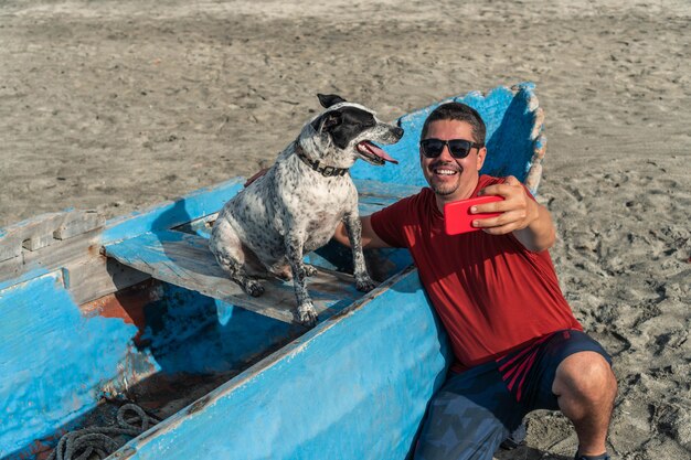 Man die een selfie maakt met zijn hond op het strand in de zomer