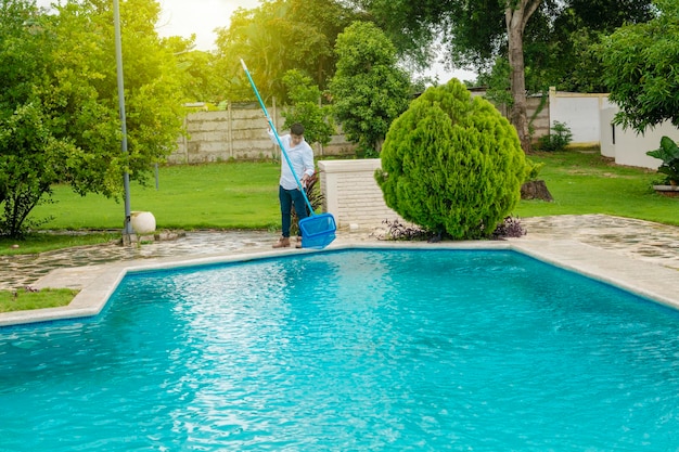 Man die een zwembad schoonmaakt met skimmeronderhoud Persoon die een zwembad schoonmaakt met skimmer zwembadreinigings- en onderhoudsconcept