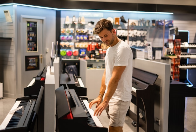 Man die elektronische piano kiest in de winkel