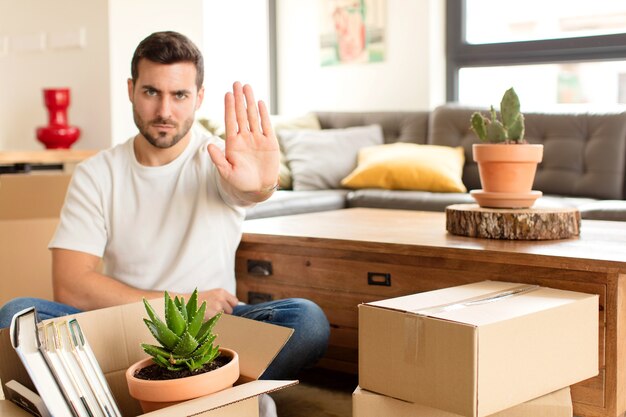 man die er serieus, streng, ontevreden en boos uitziet met een open handpalm die een stopgebaar maakt