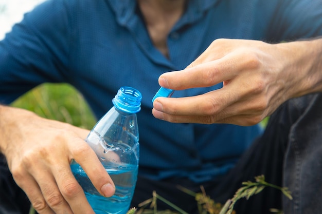 Man die fles mineraalwater opent in de buitenlucht