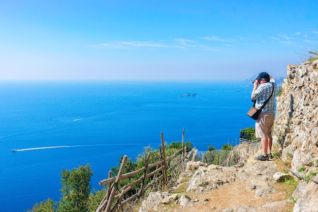 Man die foto's maakt van een prachtig landschap op Path of Gods aan de Tyrrheense Zee, Amalfikust, Italië