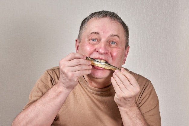 Man die gefrituurde spiering vis eet en vis vasthoudt met zijn handen voor zijn gezicht