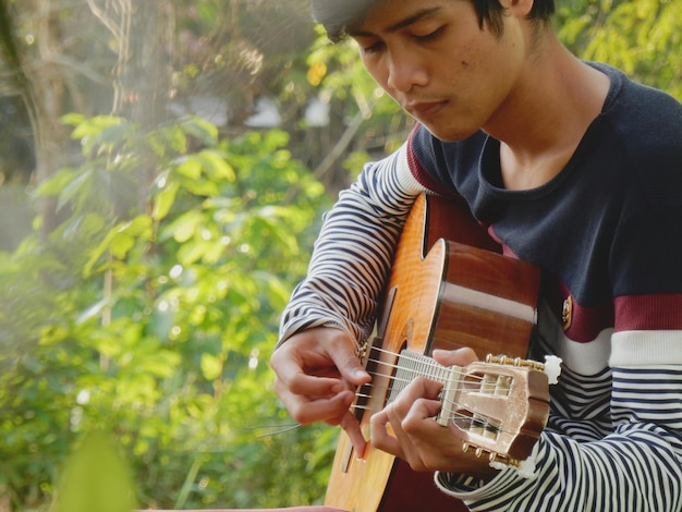 Foto man die gitaar speelt tegen planten.