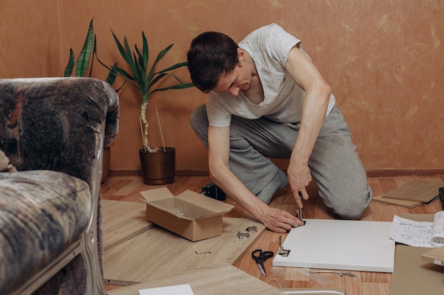 man die handmatig gereedschap gebruikt en nieuwe houten meubels in elkaar zet