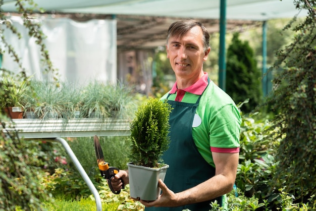 Man die in een tuincentrum staat en planten vasthoudt