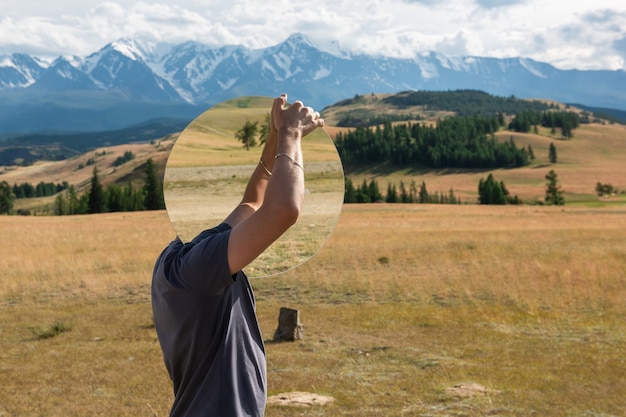 Man die in het altai-gebergte in de zomer in de kurai-steppe staat en creatieve reizen met cirkelspiegels vasthoudt