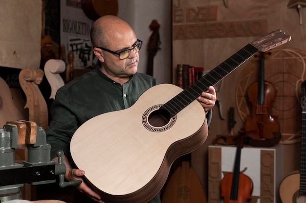 Foto man die instrumenten maakt in zijn atelier alleen