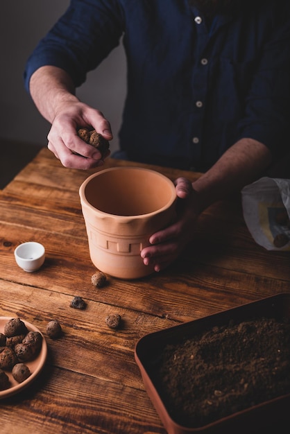 Man die kleikiezels in terracotta pot stopt