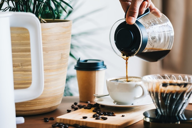 Man die koffie in een kopje giet, alternatieve koffiezetmethode, met behulp van overdruppelaar en papieren filter.