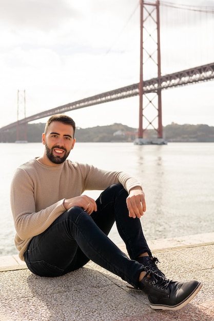 Man die lacht zittend met de brug van 25 april op de achtergrond in Lissabon