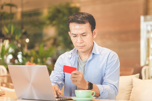 Man die laptop en creditcard gebruikt om online te winkelen een online kopershanden met een laptop en creditcard