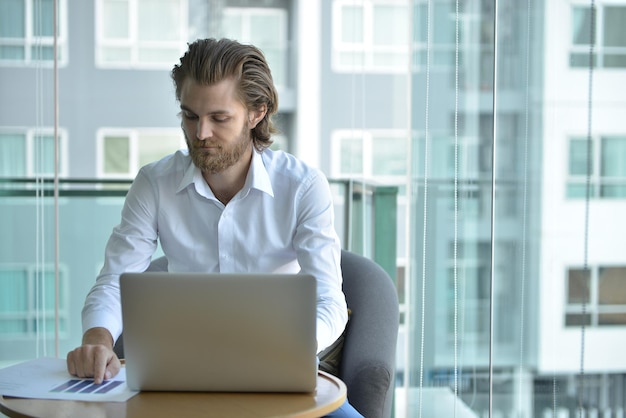 Man die laptop gebruikt terwijl hij op kantoor zit