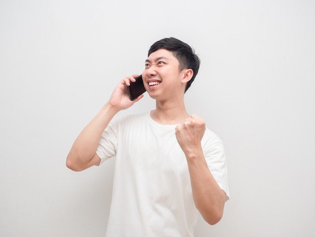 Man die met een mobiele telefoon praat, laat zijn vuist zien en voelt zich gelukkig op een witte achtergrond