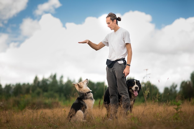 Foto man die met honden speelt terwijl hij op grasland tegen bewolkte lucht staat