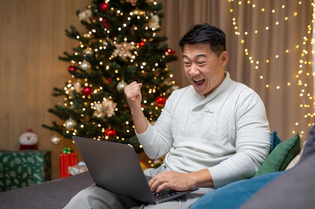 Man die nieuwjaar thuis viert en kerst-aziatische kreeg goed nieuws online lezen van laptop en