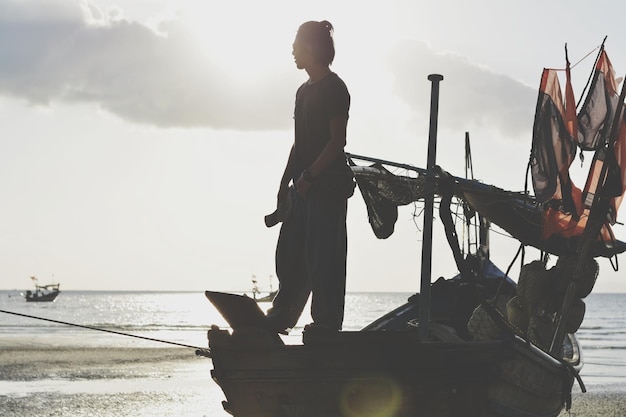 Foto man die op een boot op het strand staat