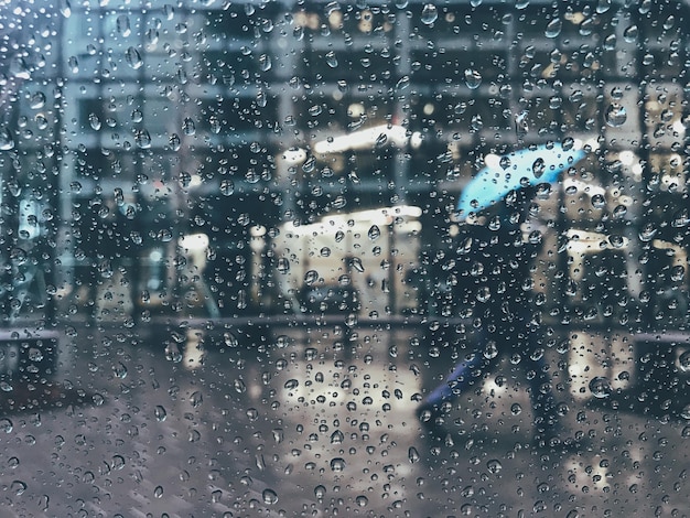 Man die op het voetpad loopt gezien door een nat autovenster tijdens het regenseizoen