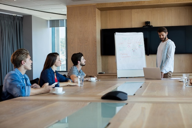 Man die presentatie geeft aan haar collega's in de vergaderruimte op kantoor