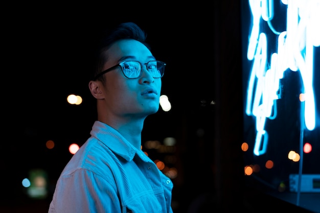 Man die 's nachts in blauw neonlicht poseert