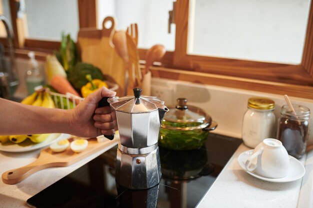 Man die 's ochtends koffie maakt in een moka-pot op het fornuis