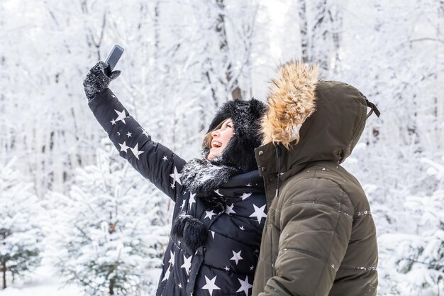 Man die selfie foto neemt jong romantisch paar glimlach sneeuw bos buiten winter