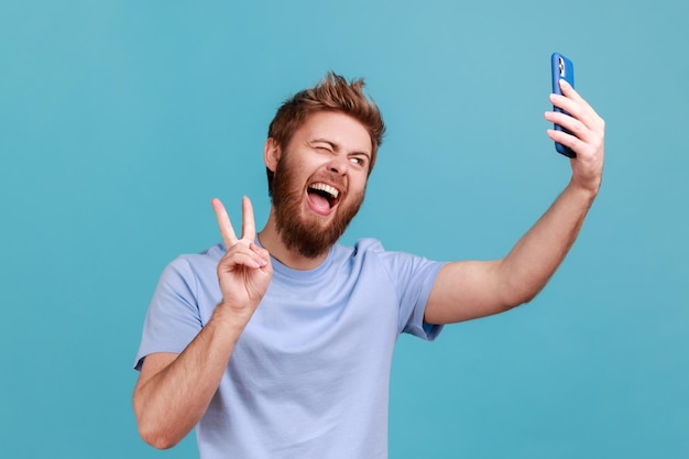 Man die selfie neemt of praat tijdens een videogesprek en een overwinningsvredesgebaar laat zien, prettige communicatie