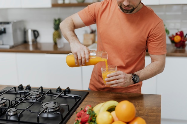 Man die sinaasappelsap in een glas giet