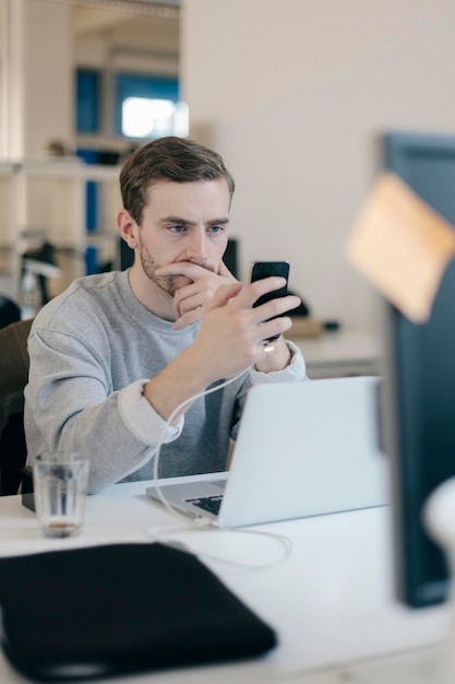 Man die sms't op zijn mobiele telefoon op kantoor.