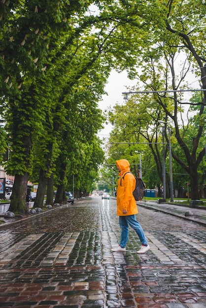 Man die straat oversteekt in geel regenjas bewolkt weer