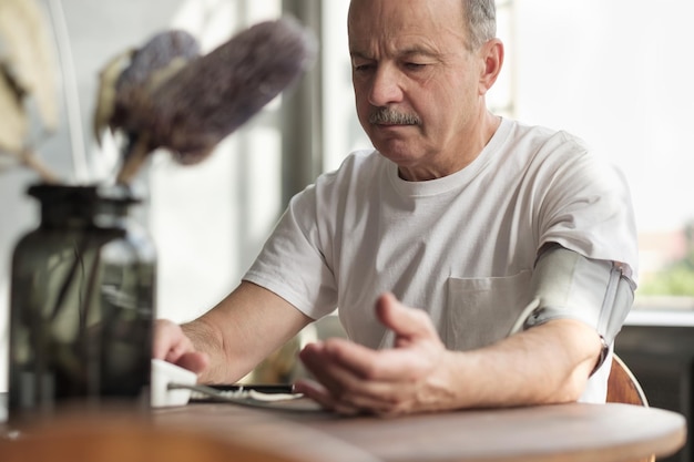 Man die thuis bloeddrukmachine gebruikt om zijn vitale statistieken te controleren