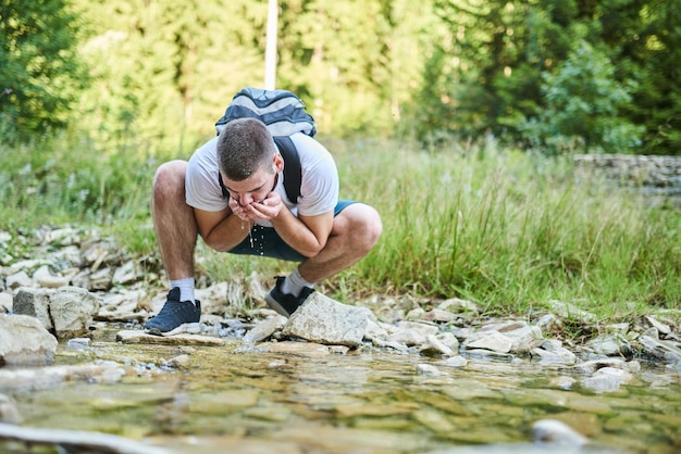 Man die vers bronwater drinkt tijdens het wandelen. Selectieve focus. Hoogwaardige foto