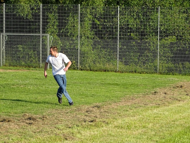 Man die wegkijkt terwijl hij op het gras loopt