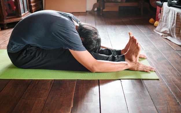 Man die yoga beoefent zittend in Zittende voorwaartse buiging oefening paschimottanasana pose Gezond leven