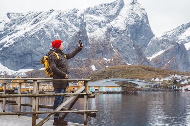 Man die zelfportret maakt met een smartphone tegen de achtergrond van besneeuwde bergen en meren